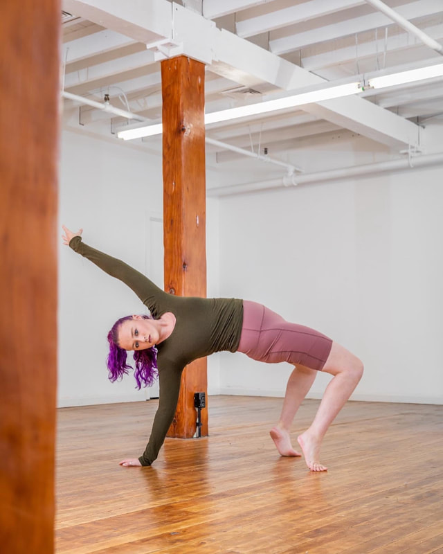 Purple haired dancer holds a one handed backbend in forced arch