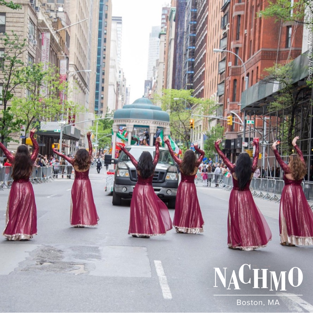 Six women walking Through New York City streets With arms in the air