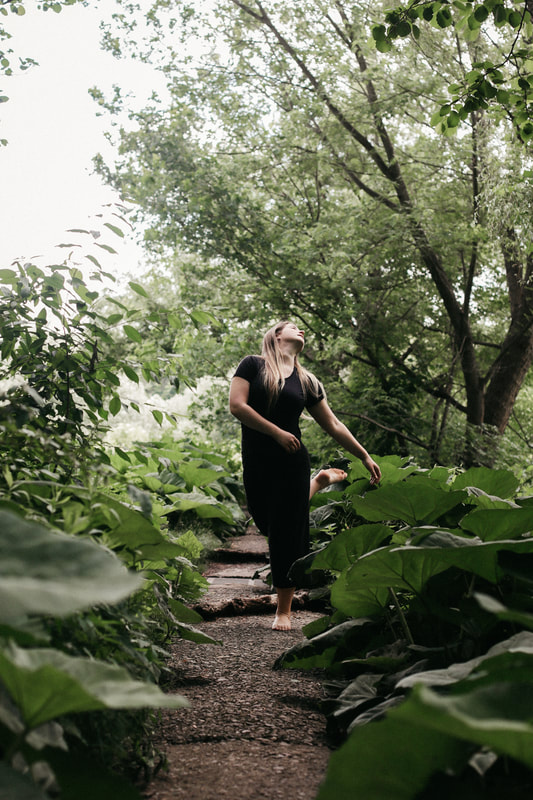 White woman walking Head and arms reach to the right On a wooded path