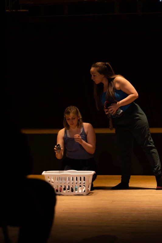 Two white women looking into a laundry basket of socks