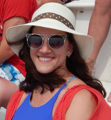 Headshot of woman In sunglasses and beach hat  She smiles at camera