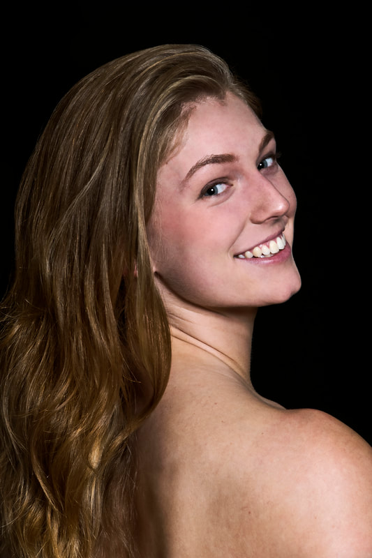 Headshot of white woman Looks over shoulder and smiles Long hair falls down back