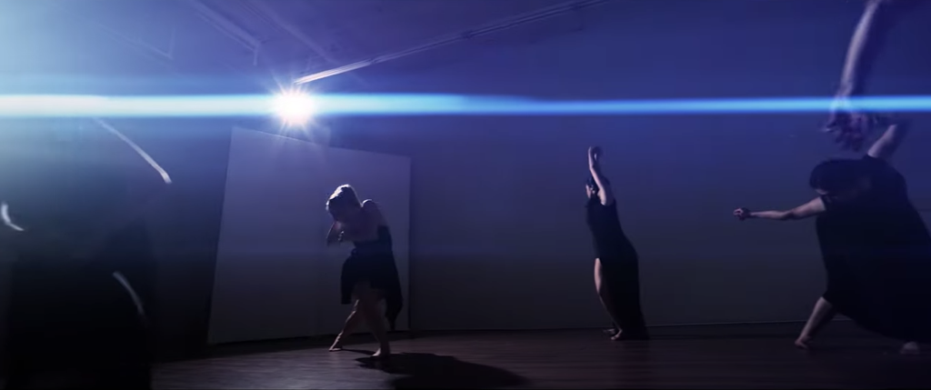 Four dancers in room  Light sends blue streaks across room All strike different pose