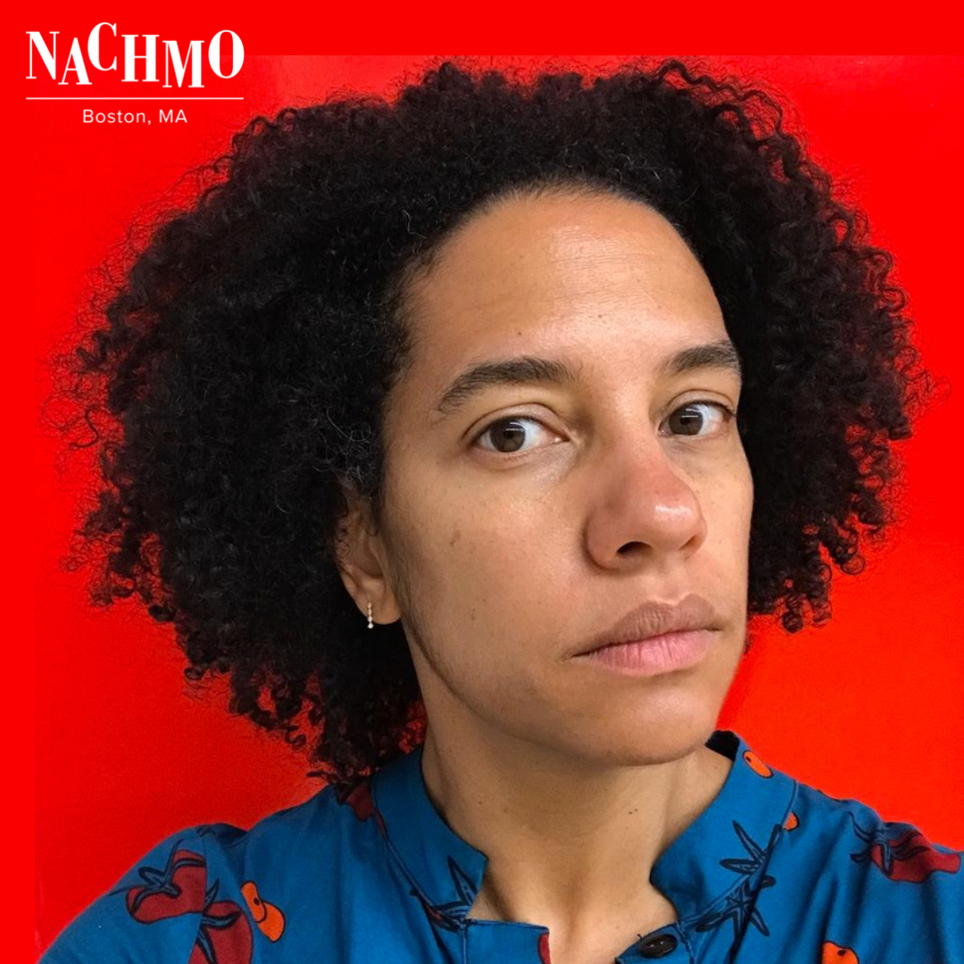 Black woman staring
At the camera wearing blue
Before a red wall