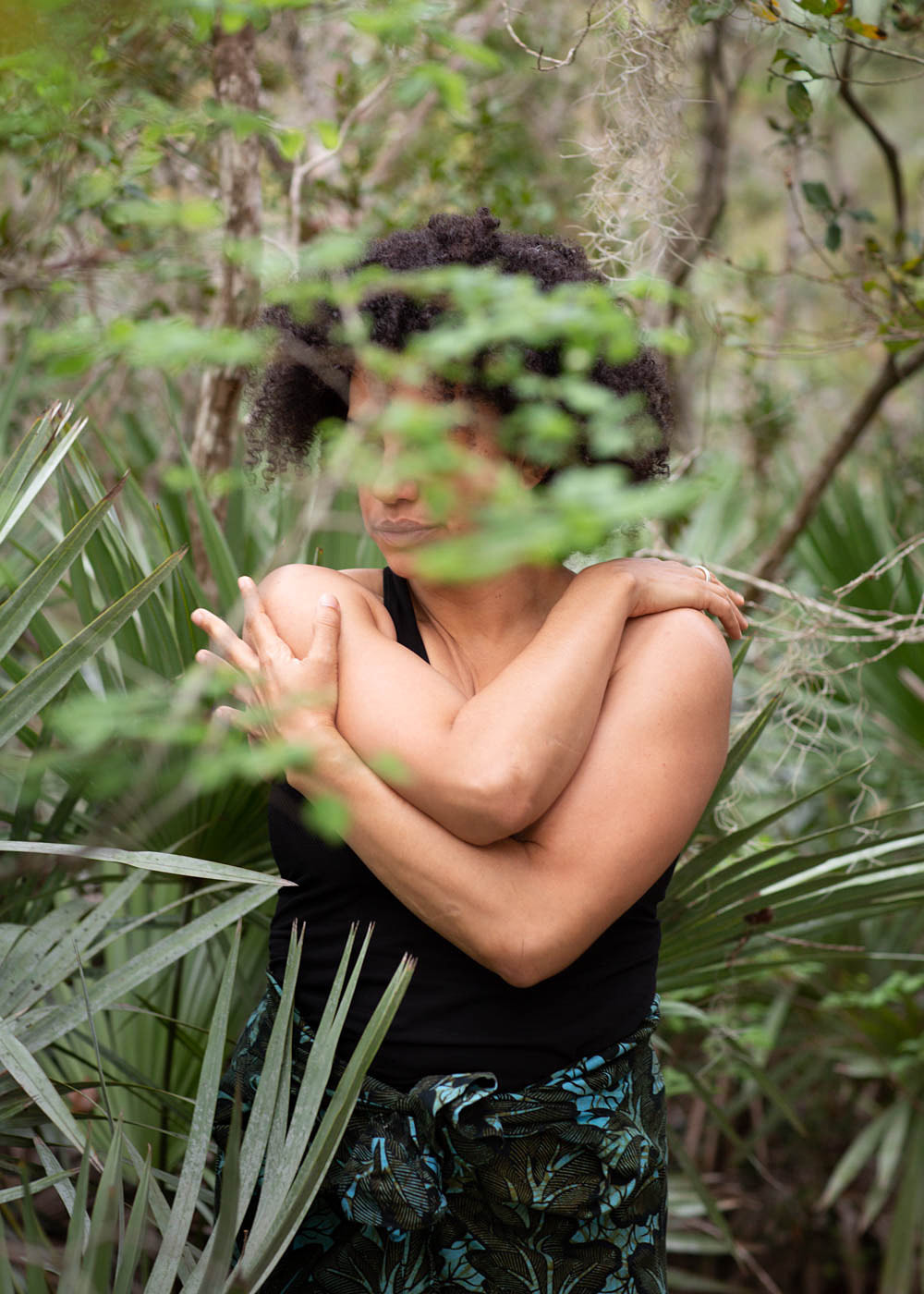 Biracial woman  with her arms around herself  Hidden by a tree