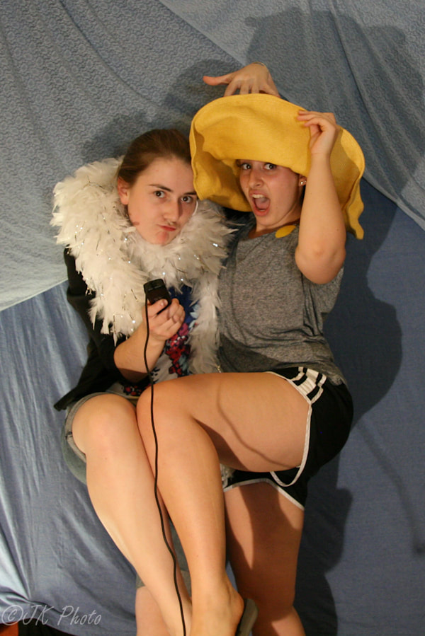 Two women in a hat and a feather boa in a photobooth