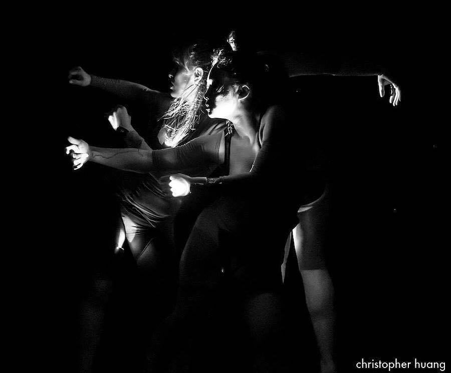 Dancers in all black White light streams illuminate Some parts of bodies