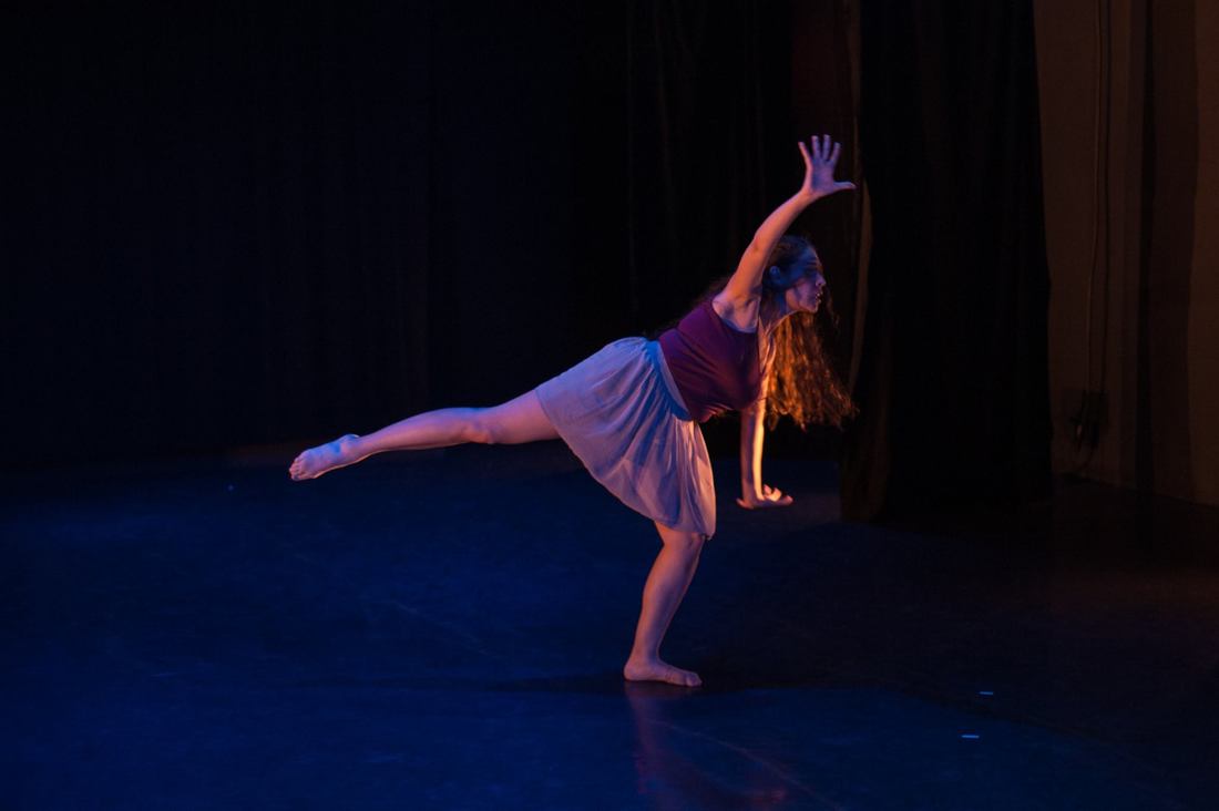 Dancer on a stage One leg to side, arms waving Purple top and skirt
