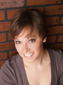 Headshot of person Short brown hair, grey eyes, smiling Against red brick wall 