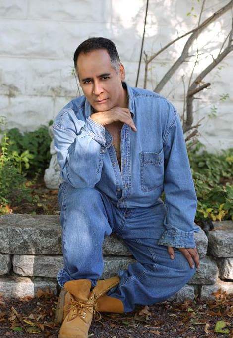 Man in all denim poses outside with chin on hand