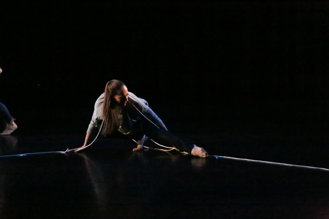 White woman on stage Rope over shoulders, leg out Surrounded by black 