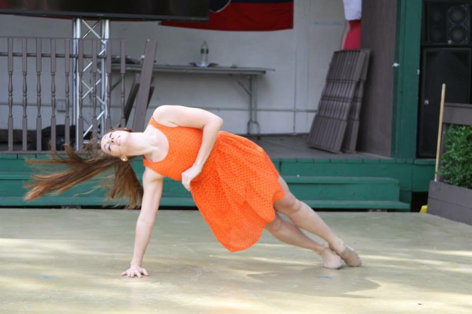 Dancer in orange dress, Balances on arm and legs, Hair swinging behind 
