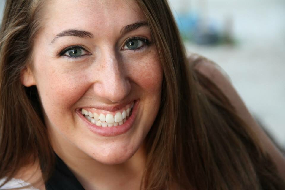 Headshot of white woman Long brown hair, grey eyes, smiling Freckles on her face