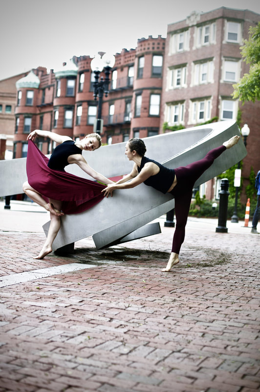 In maroon and black  Two dancers, spiral sculpture Strike balletic pose