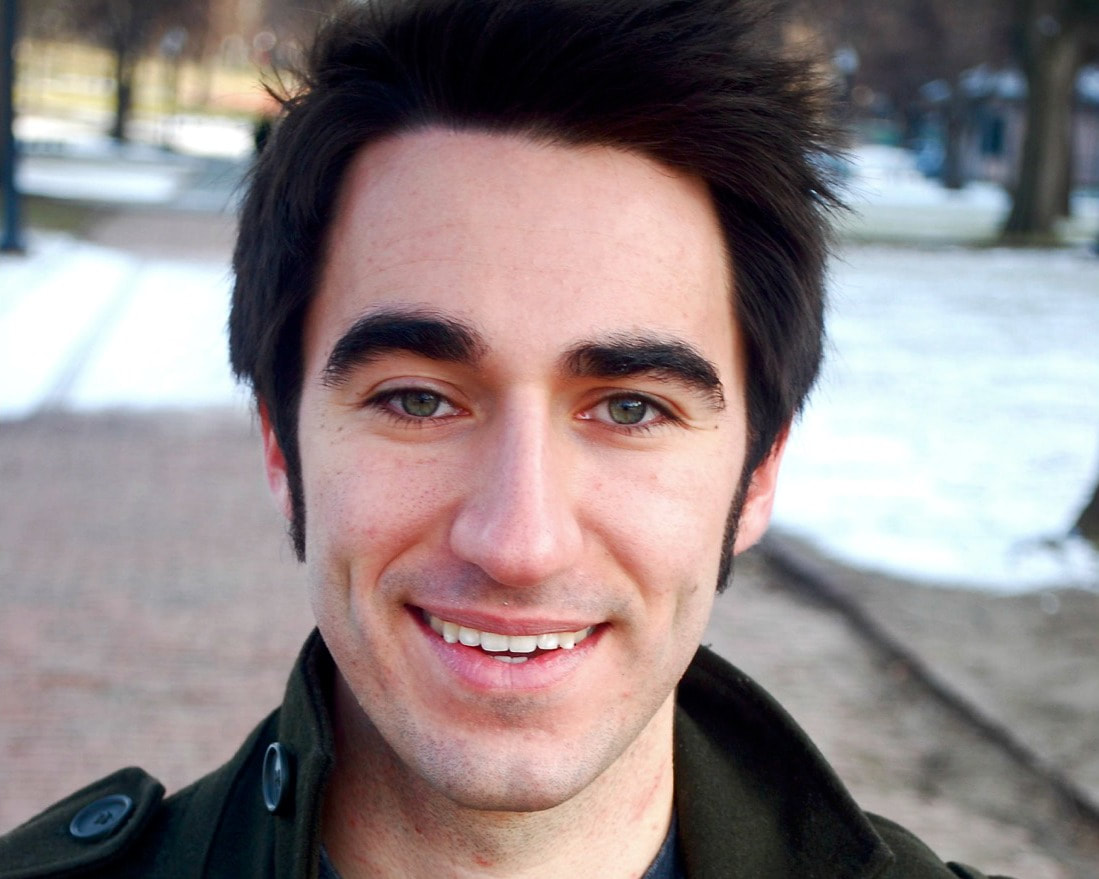 Headshot of person, Dark hair, dark eyes, and a smile, Snowy ground behind 