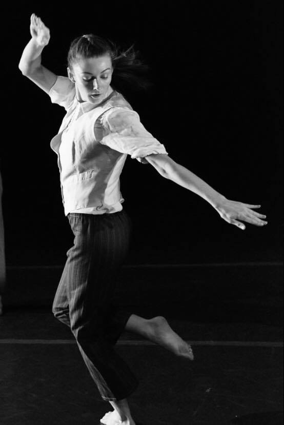 Black and white photo Dancer on stage, looks at foot Off the ground and back 